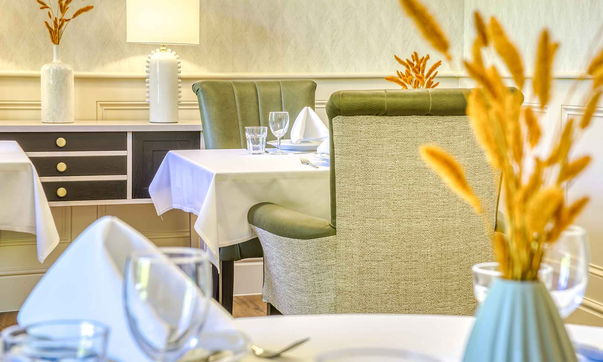 A tasteful dining room showing the back of the Toledo high back chair, a dining table with a white cloth and the Linford console table.